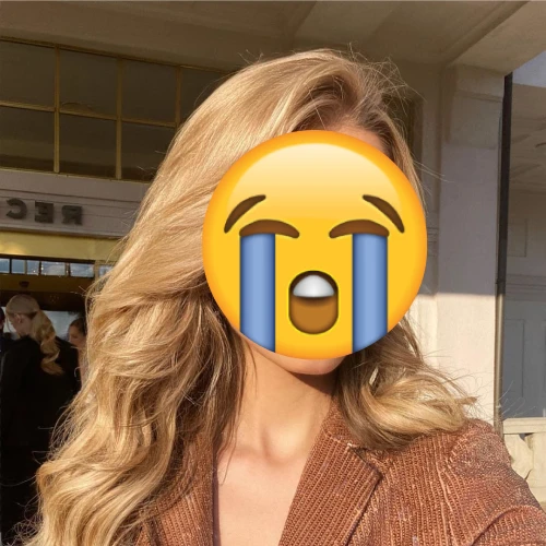 Woman outdoors with her face covered by a crying emoji